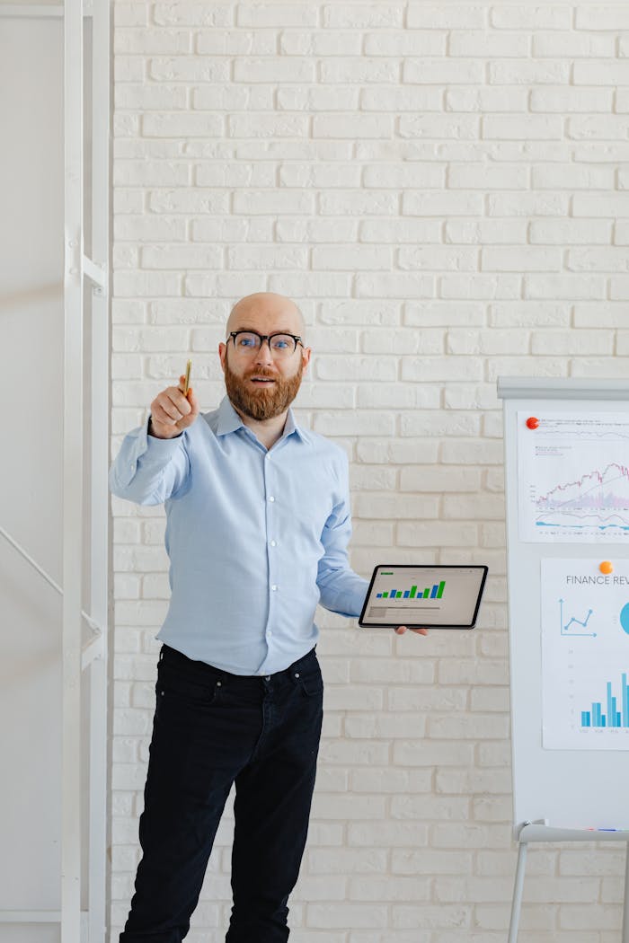 A businessman presents growth charts using a tablet and flipchart in an office setting.